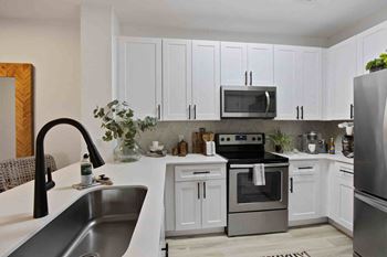 a white kitchen with stainless steel appliances and white cabinets